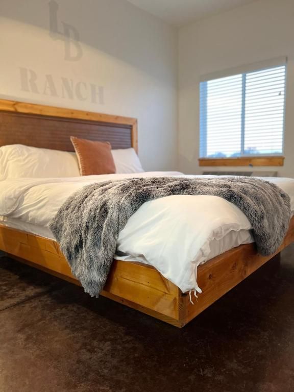 Bedroom with wooden bed, gray throw blanket, and window with blinds