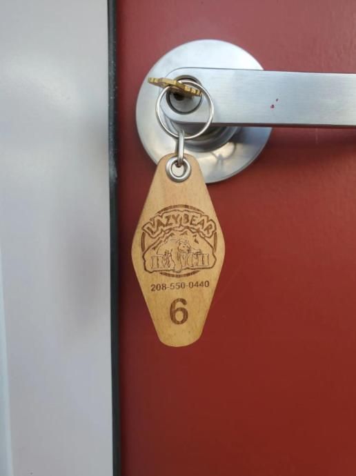Close-up of a keyed door lock with a tan tag hanging from it on a red door.