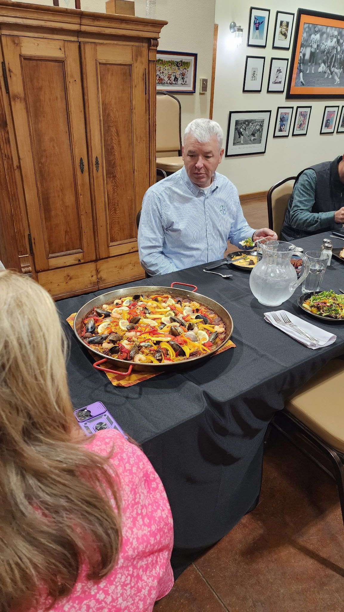 People seated at a table with bowls of food in a room with framed photos on the wall