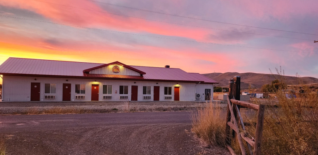 Rural house at sunset with pink-orange sky and mountains in the background