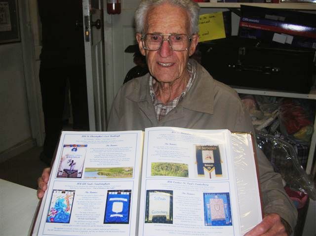An elderly man is holding a book with pictures on it