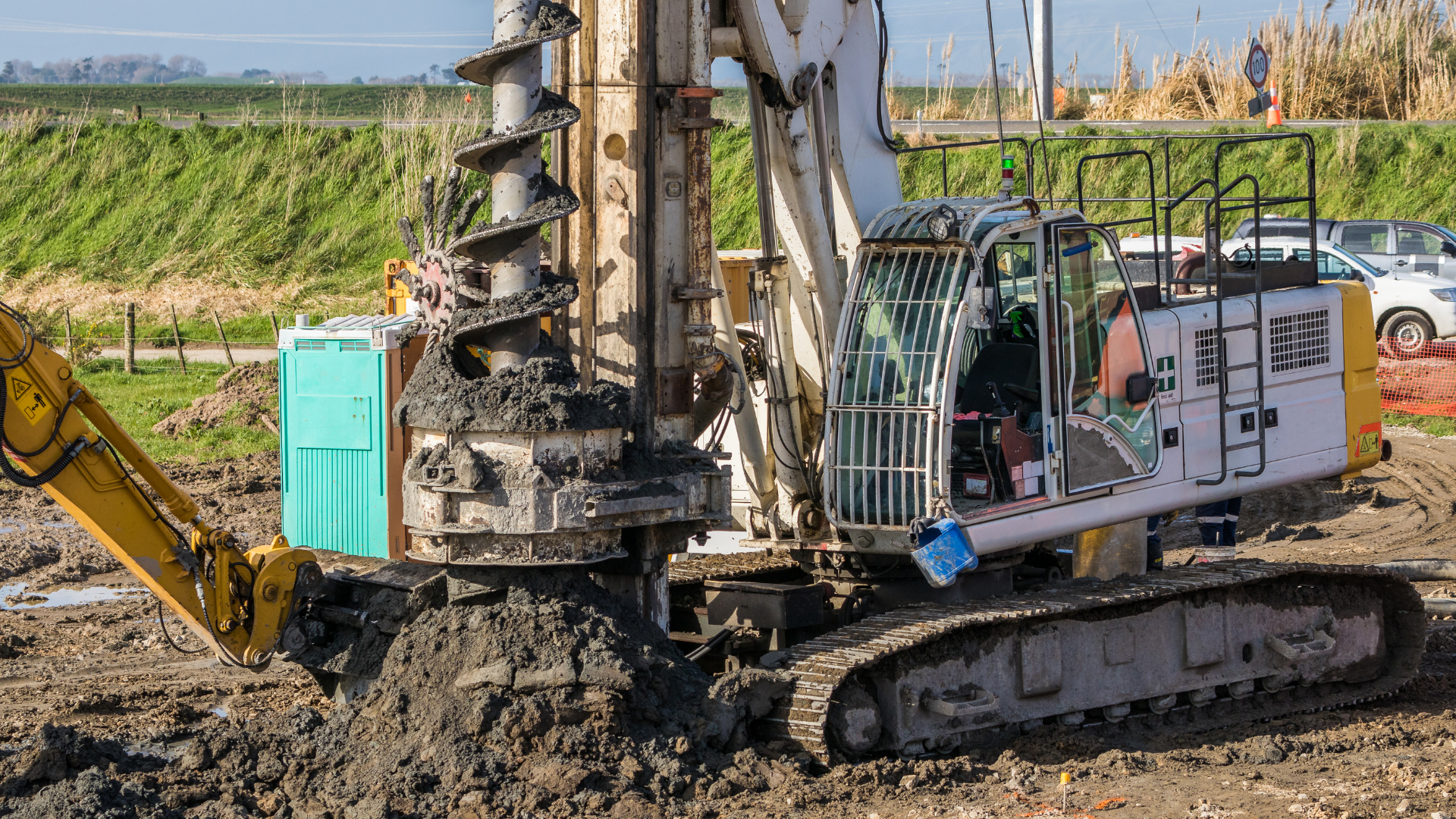 A white PVC pipe capped at the top, standing upright in a pile of dirt and gravel in an outdoor area.