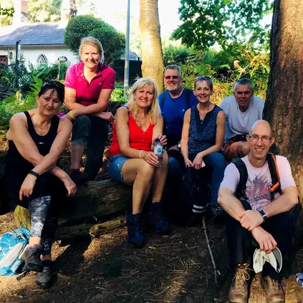 A group of people sitting and relaxing on a log after an enjoyable day’s hiking in Cheshire.