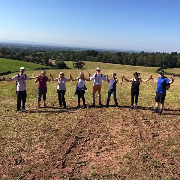 People having fun standing in ploughed field holding hands and posing as scarecrows.
