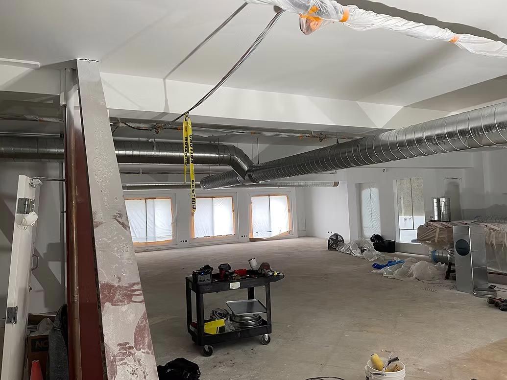 Partially renovated room with exposed ceiling beams, small windows, and construction materials on the floor