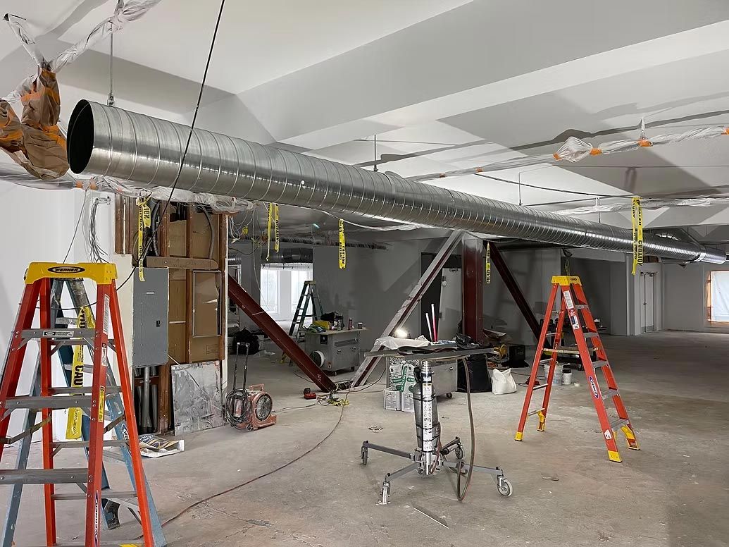 Construction site with red ladders and exposed ductwork in an unfinished interior room
