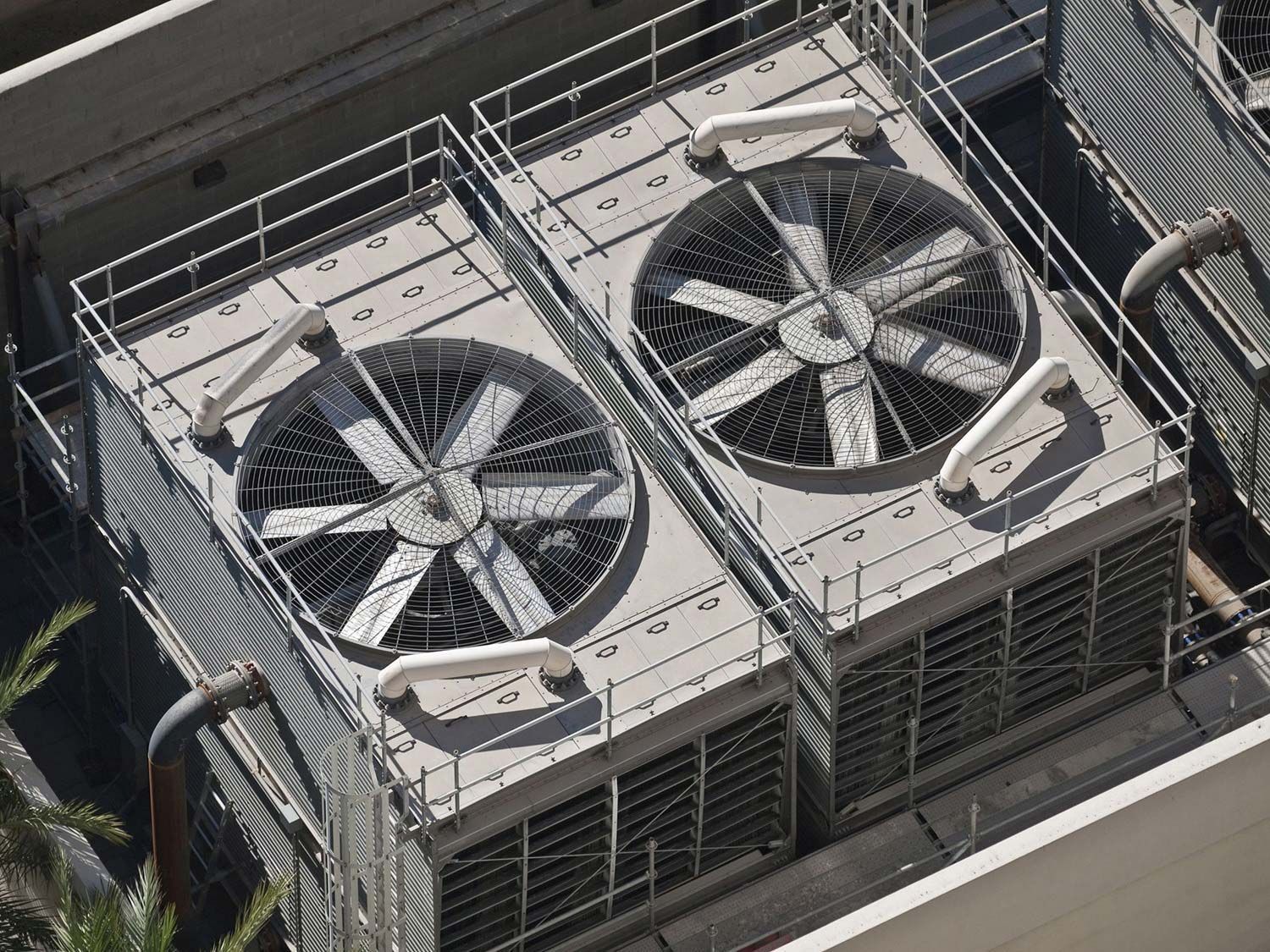 Two rooftop HVAC units with large fans behind a metal safety cage.