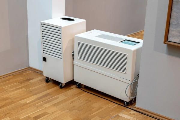 Two white portable air conditioners on a wood floor in a room