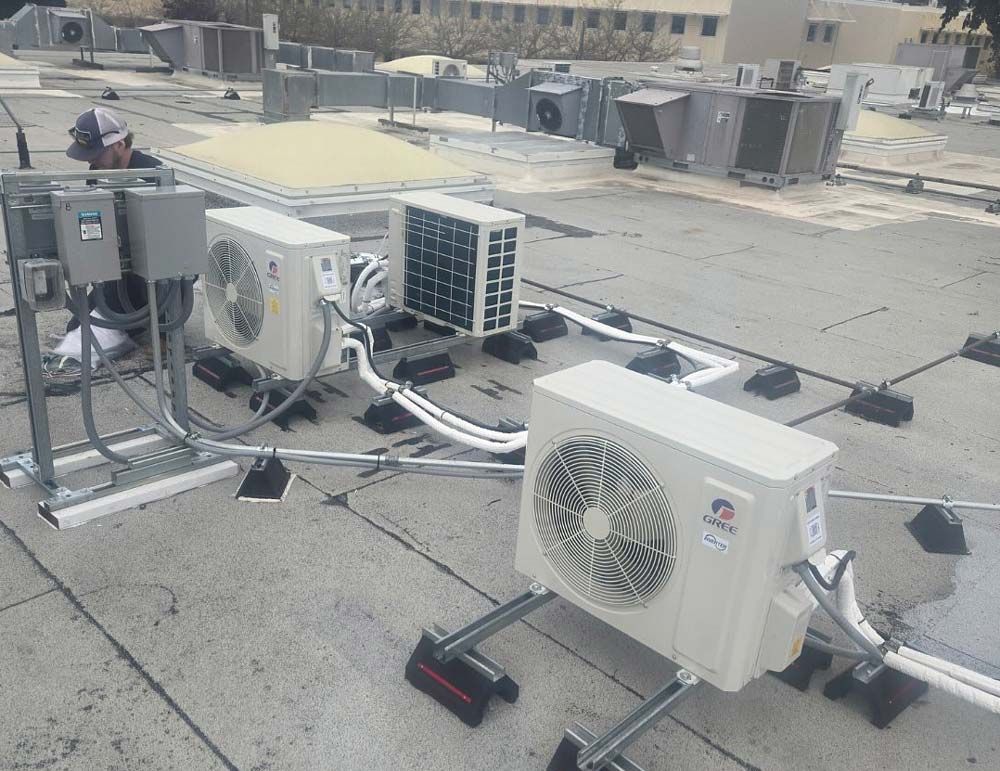 Rooftop HVAC units and electrical equipment on a flat commercial roof under bright sun