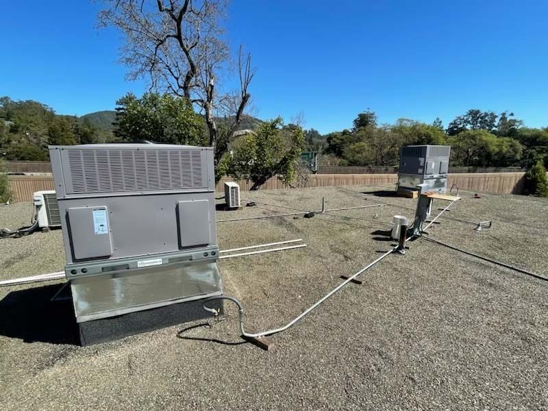 Outdoor weather monitoring equipment on gravel under a clear sky, with two metal instrument units and cables