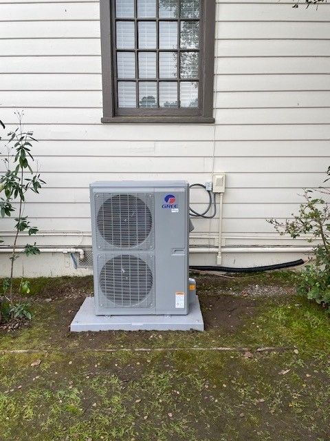 Outdoor air conditioner unit beside a house wall beneath a window