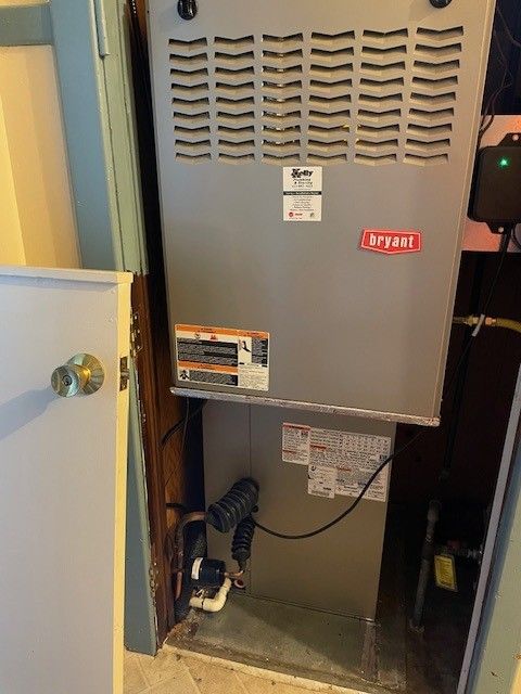 Open furnace cabinet with red “Bypass” label in a utility closet
