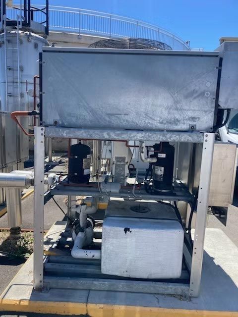 Industrial rooftop machinery with pipes, tanks, and a metal frame under a blue sky