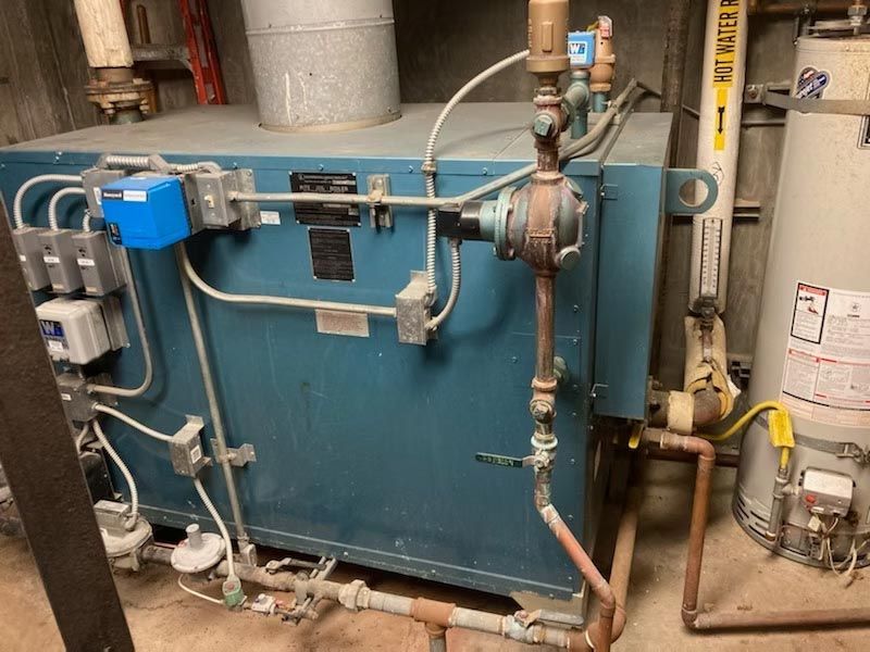 Industrial boiler with blue panel, pipes, valves, and gauges in a mechanical room