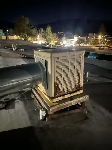 Large rooftop HVAC unit with a connected duct at night on a flat roof