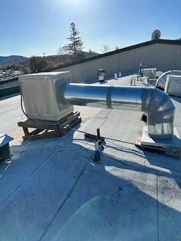 Rooftop HVAC ductwork with metal vents and a bright blue roof under clear sky