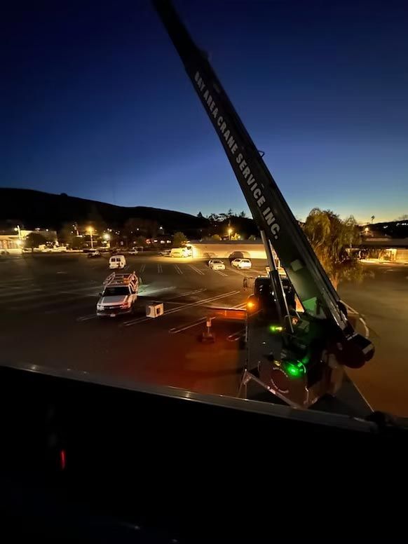 Tow truck lifting a car at night in a lit parking lot with mountains in the background