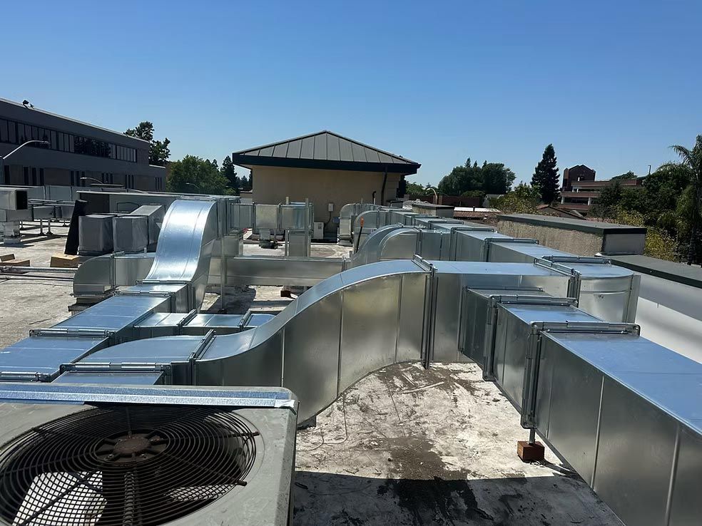 Rooftop HVAC ductwork and large metal ventilation units on a flat industrial building roof