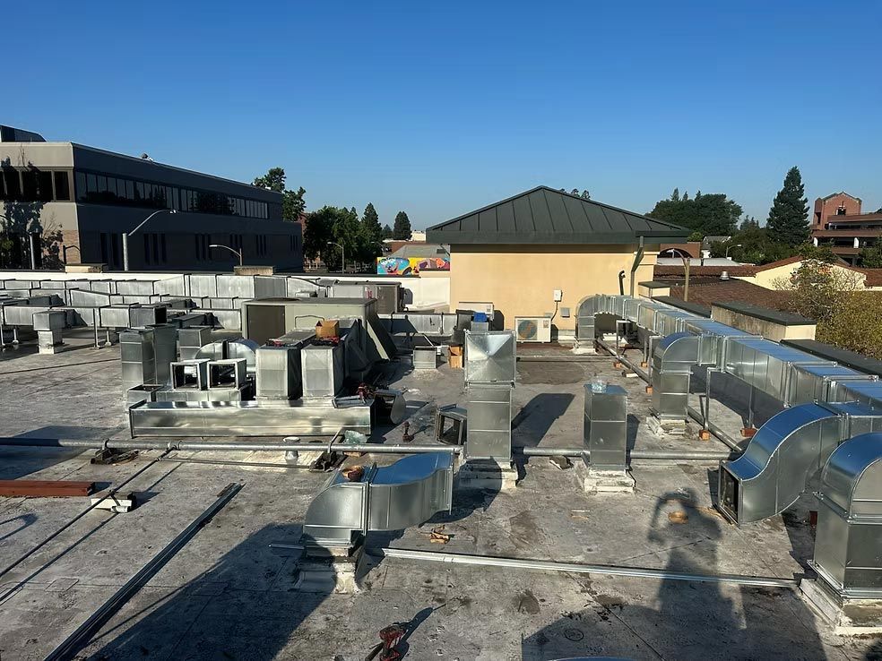 Rooftop HVAC ductwork and metal vents on a flat commercial roof under clear daylight
