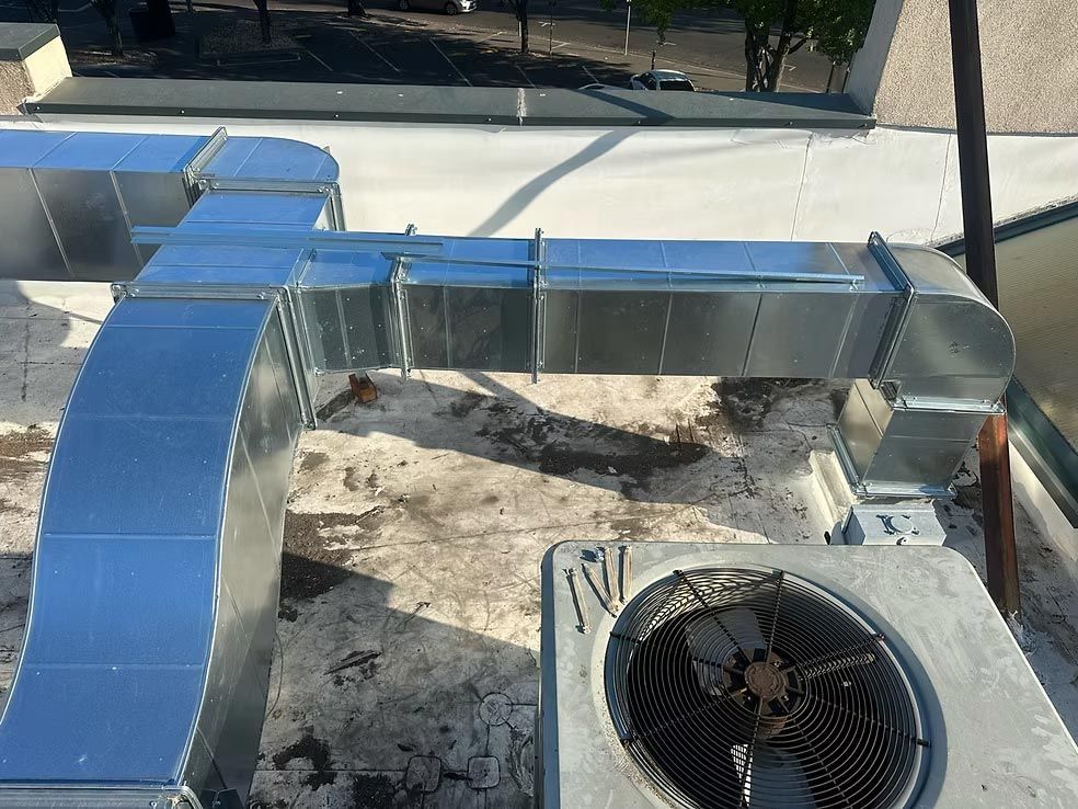 Blue rooftop HVAC ductwork beside a circular rooftop fan unit.