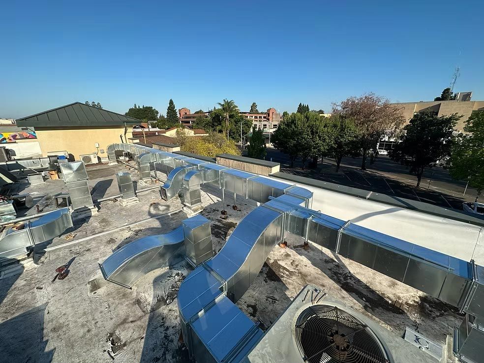 Rooftop HVAC ducts and vents on a flat roof under a clear blue sky