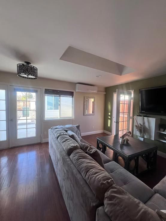 Modern living room with gray sectional, coffee table, TV, and sliding glass doors letting in daylight