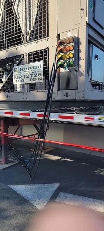 Cargo truck with a metal ladder leaning against its side on a city street.