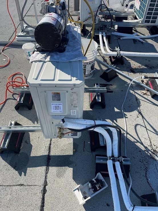 Outdoor electrical equipment and conduit on a rooftop, with cables and a white utility box.