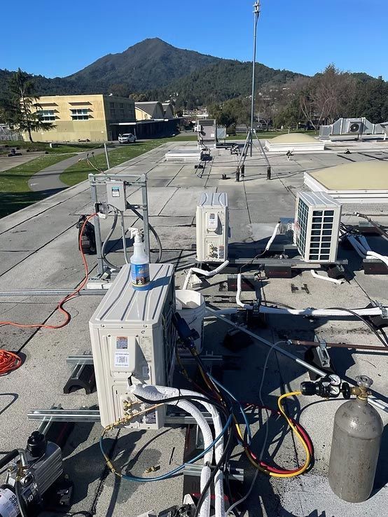 Rooftop HVAC units and vents on a flat roof with mountains in the background.