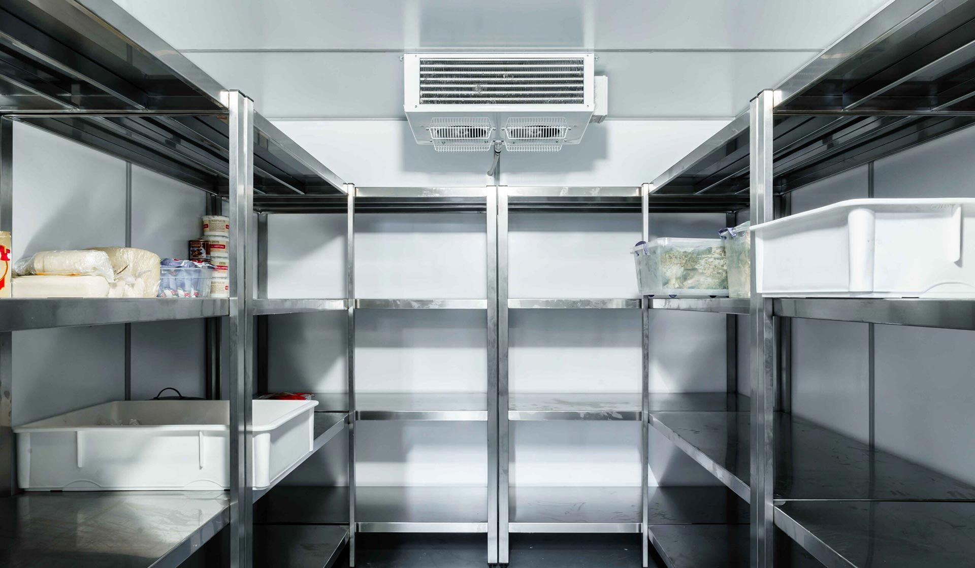 Empty stainless steel walk-in refrigerator with metal shelving and white bins