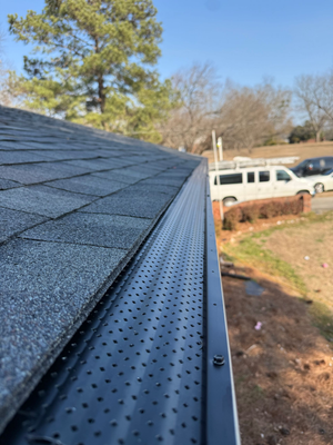 Close-up of a dark gray shingled roof with a gutter along the edge