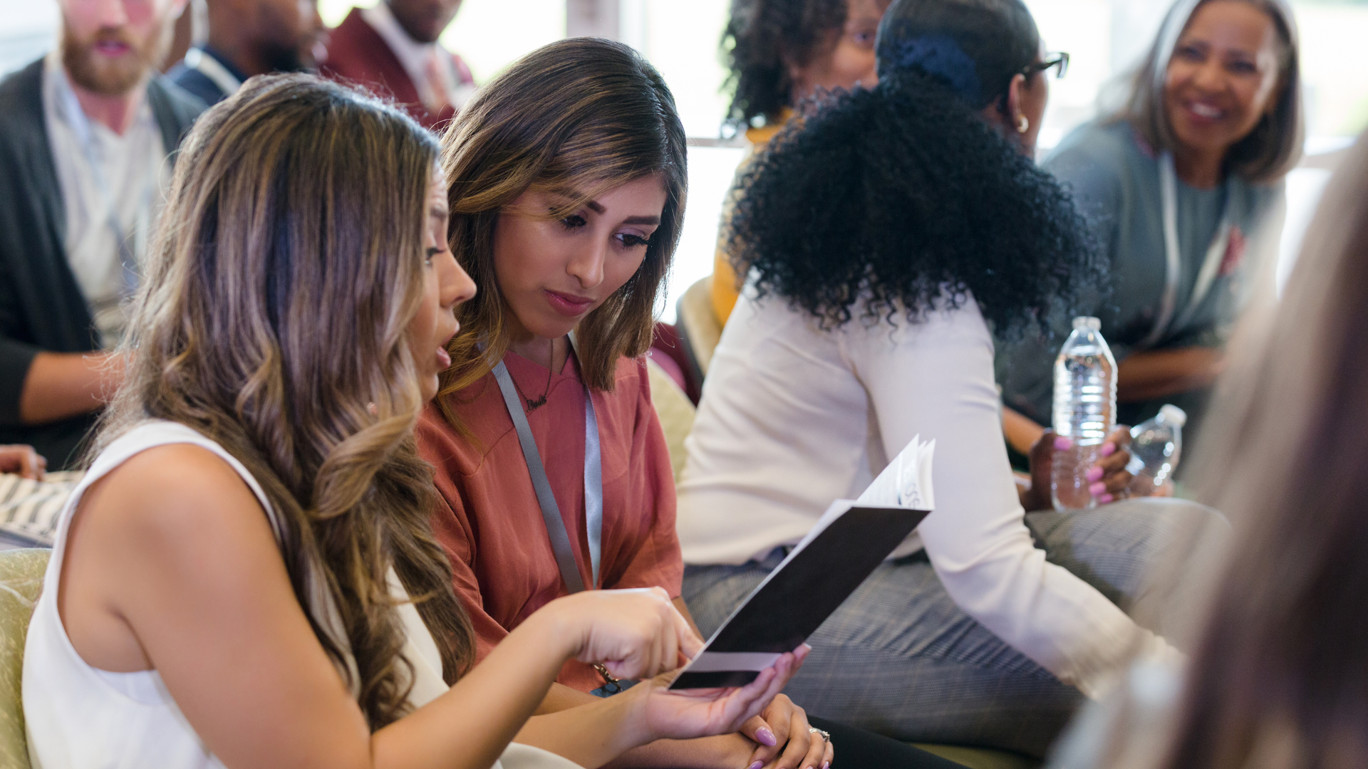 A smiling event coordinator assisting an attendee at a tech-forward check-in counter.