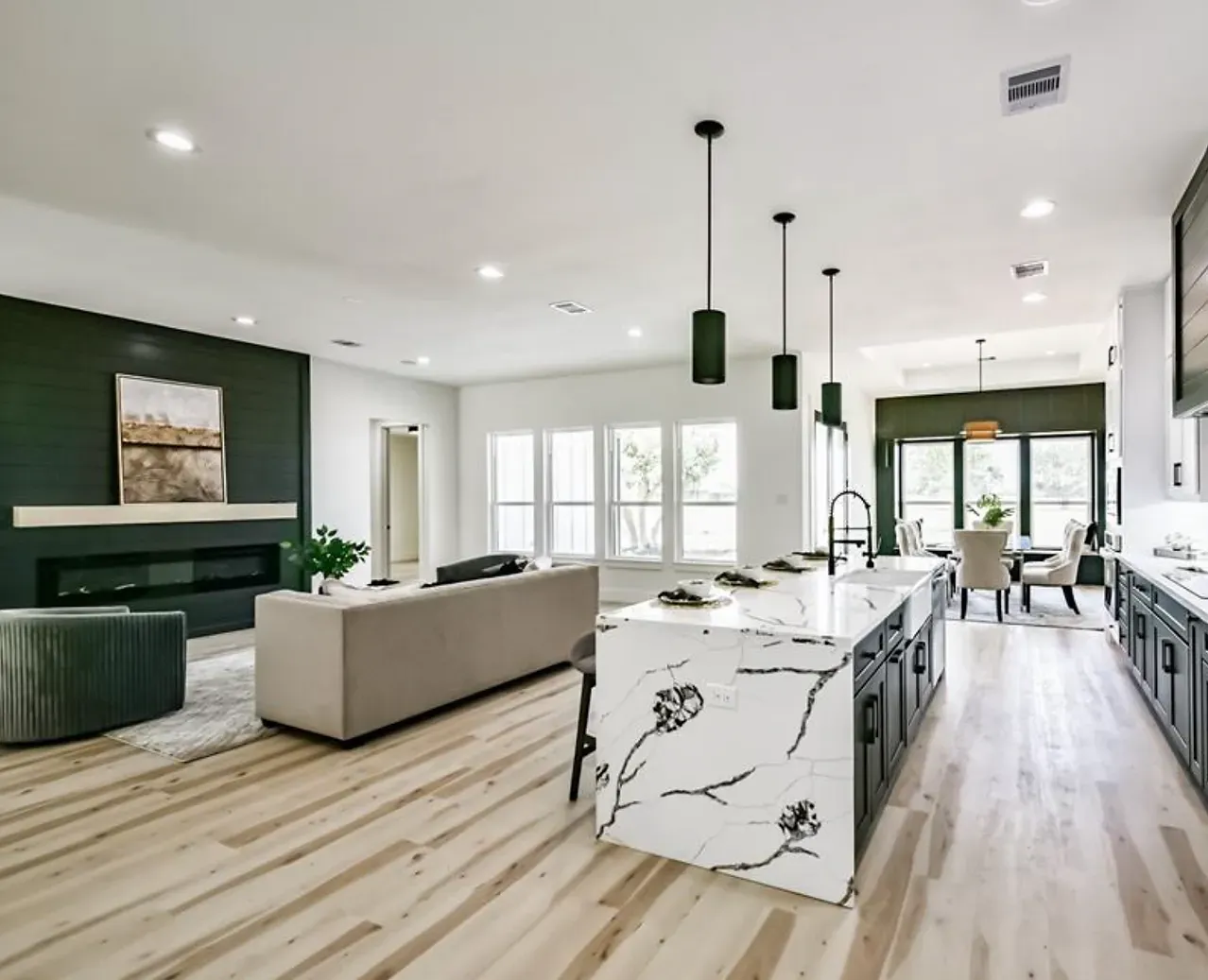 A living room and kitchen in a house with a large island in the middle.