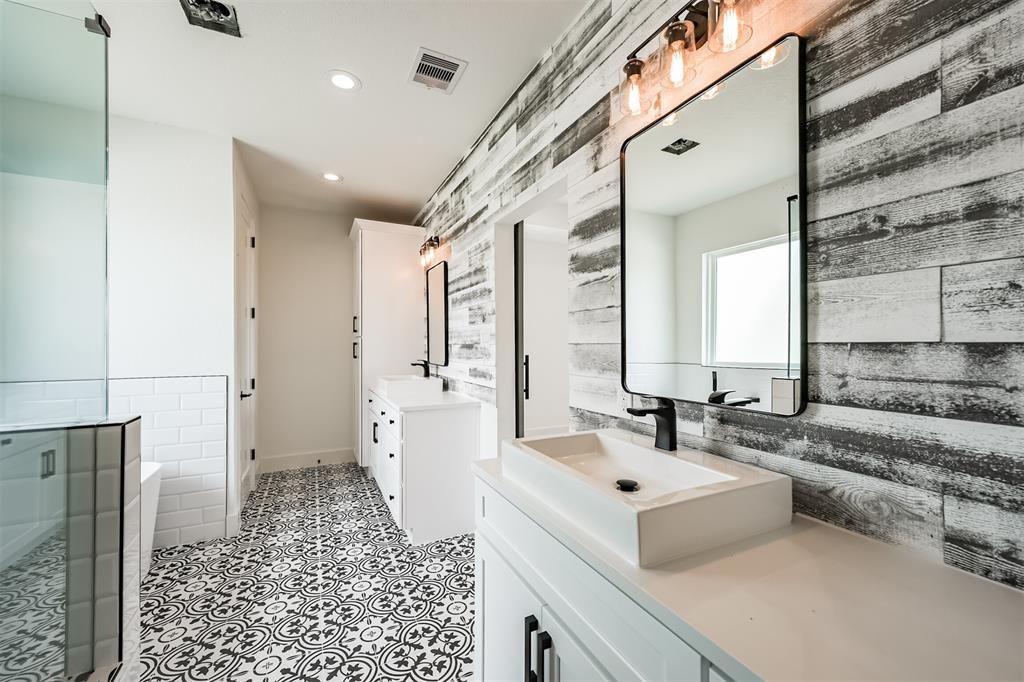 A bathroom with two sinks , a mirror and a walk in shower.