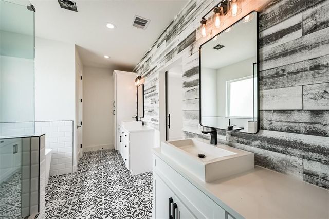 A bathroom with two sinks , a mirror and a walk in shower.