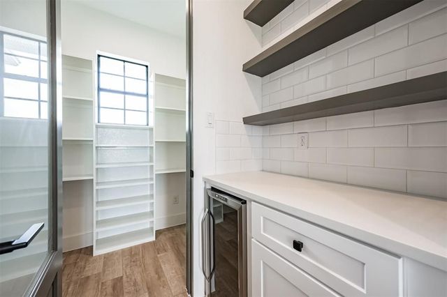A pantry with a refrigerator , shelves , and a mirror.