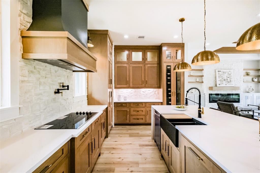 Bright modern kitchen with wood cabinets, white countertops, black island sink, and brass pendant lights