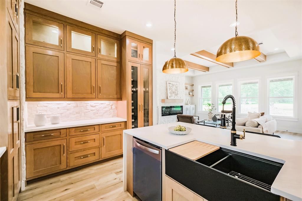 Bright, modern kitchen with wood cabinets, white island, and gold pendant lights