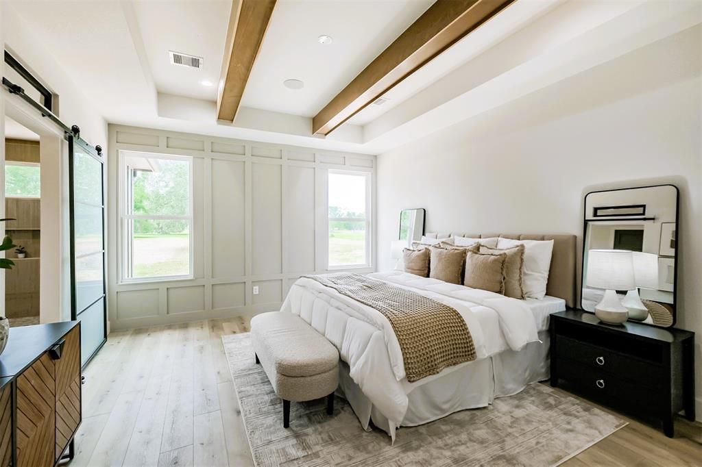 Bright modern bedroom with a bed, bench, mirrors, and large windows with natural light