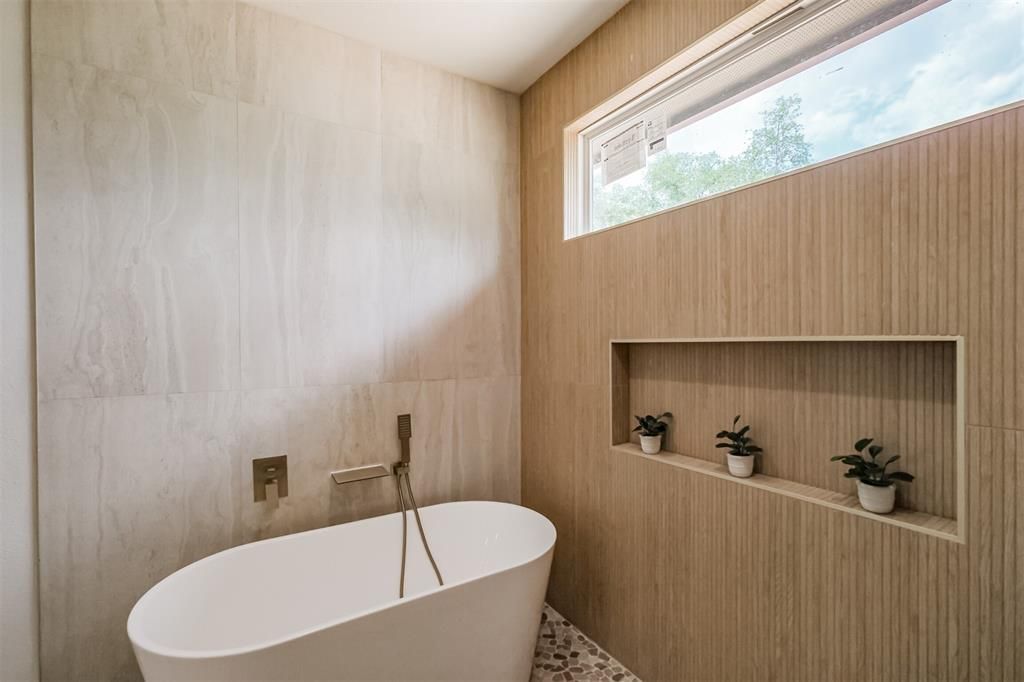 Minimalist bathroom with a white tub, wood-paneled walls, and a built-in shelf with small plants