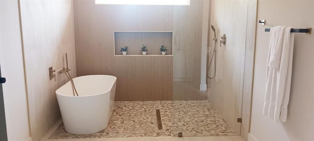 Minimalist bathroom with freestanding tub, walk-in shower, and pebble-tile floor