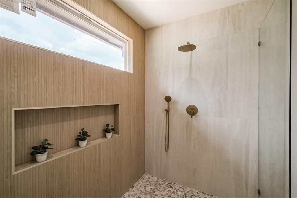 Modern bathroom with walk-in shower, wood slat wall, niche shelves, and brass fixtures