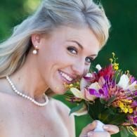 Smiling woman with blonde hair holding a colorful bouquet of flowers outdoors