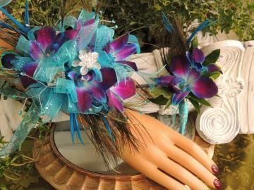 Mannequin hand wearing turquoise and purple feathered floral flower wrist corsage with lace and peacock accents