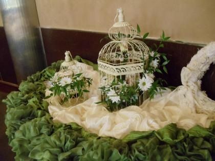 Decorative white birdcages with flowers on green and cream fabric display