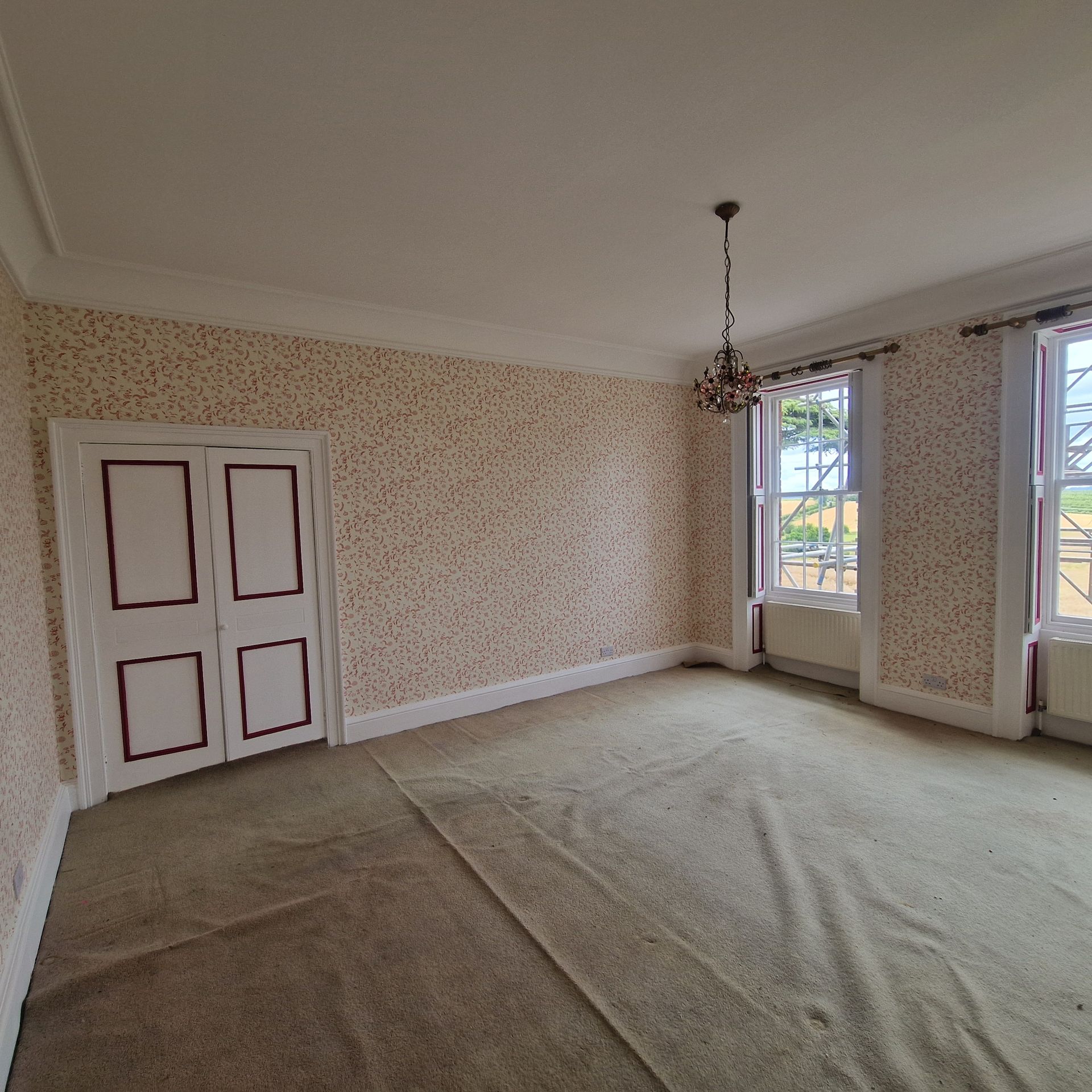 Redecorated bedroom in Cotswold with new patterned wallpaper and doors painted with a coloured trim