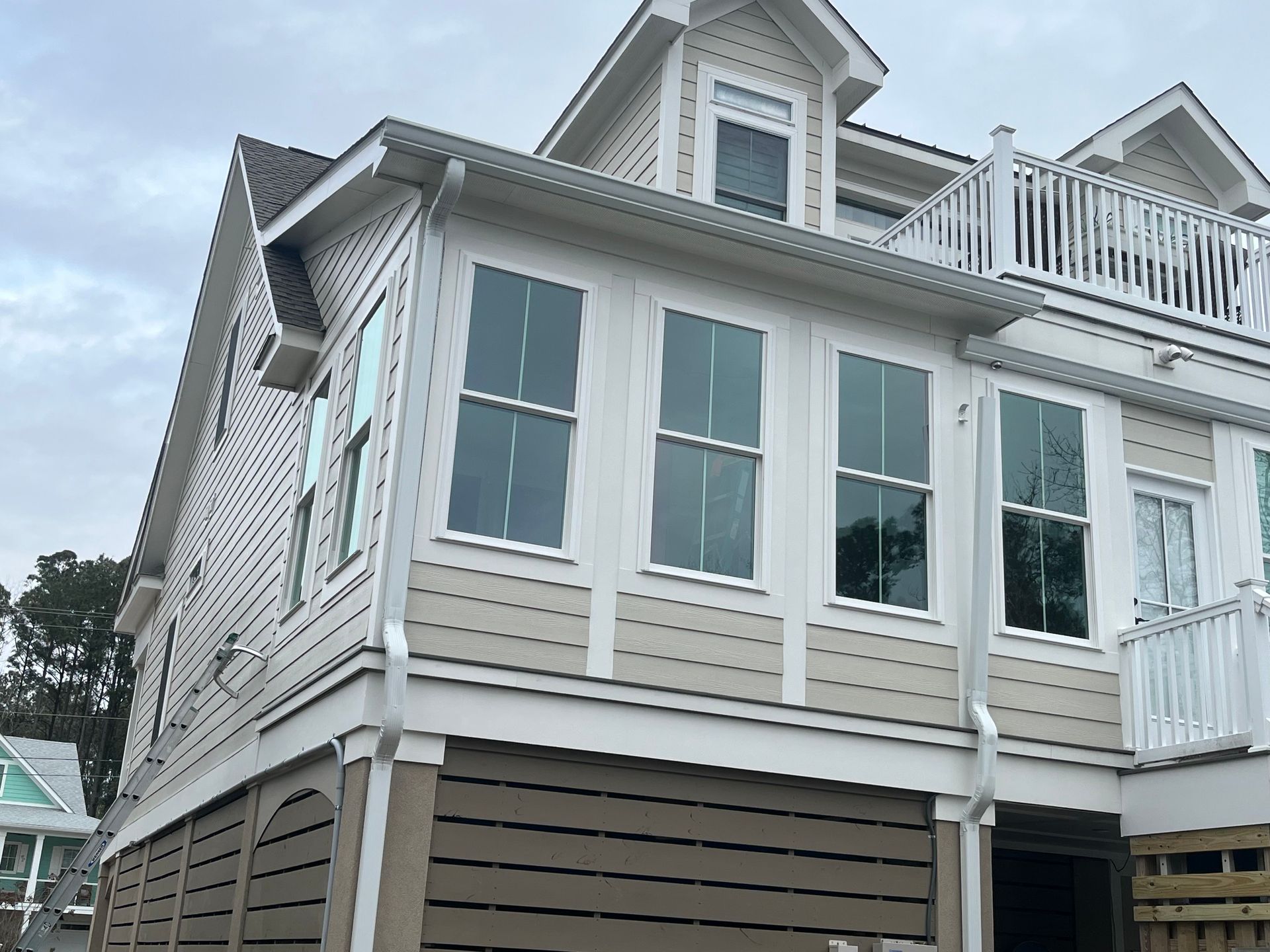 Beach house exterior with gray siding, white trim, and windows under a cloudy sky