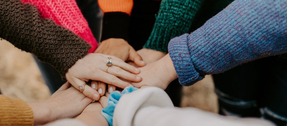 A group of people are putting their hands together.