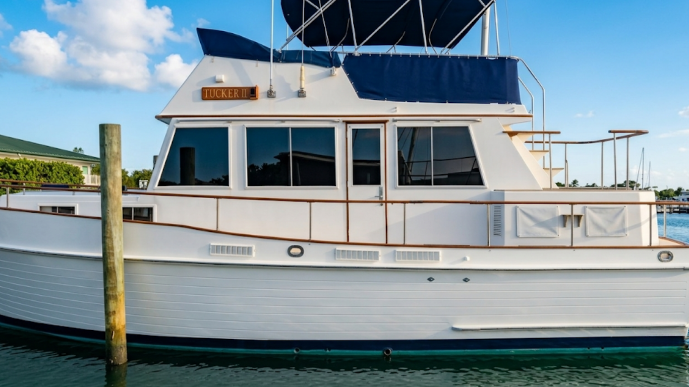 Front view of a boat cabin with dark windows and blue cushions on a white deck.