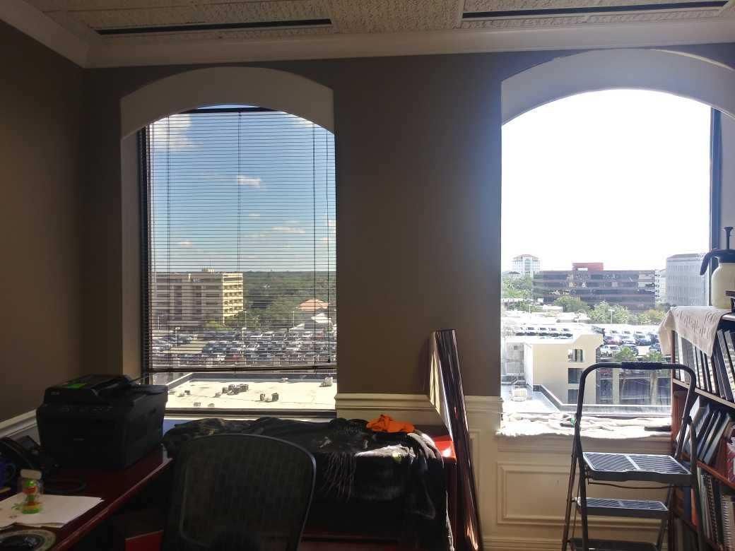 Office interior with two arched windows, desks, and a city view outside